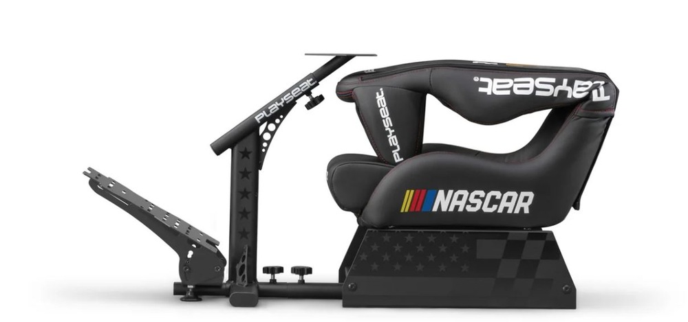 Boční pohled na černé sedadlo závodního simulátoru s tématikou NASCAR. Sedadlo má loga a barevné pruhy, má nastavitelnou základnu pedálů a robustní rám.