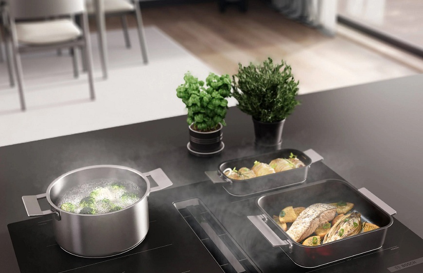 Varná deska Bosch s odsáváním, na které se právě připravují 3 pokrmy různých velikostí