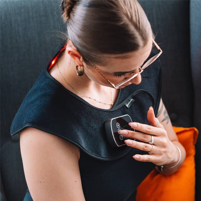 Žena sedící v křesle si nastavuje ovladač LED terapie šíje Bluetouch U1283 během domácí relaxace