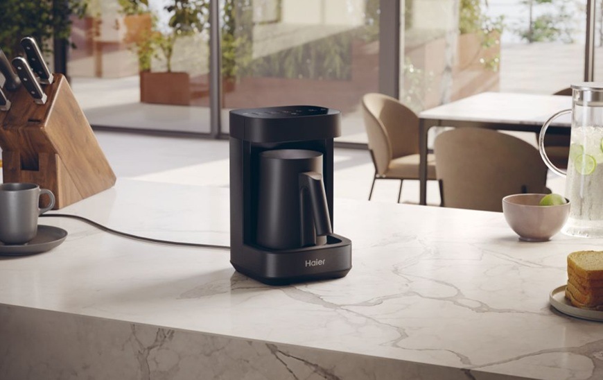 Napěňovač mléka Haier HMB5A 011 Multi Beverage I-Master Series 5 je položen na moderní kuchyňské lince.