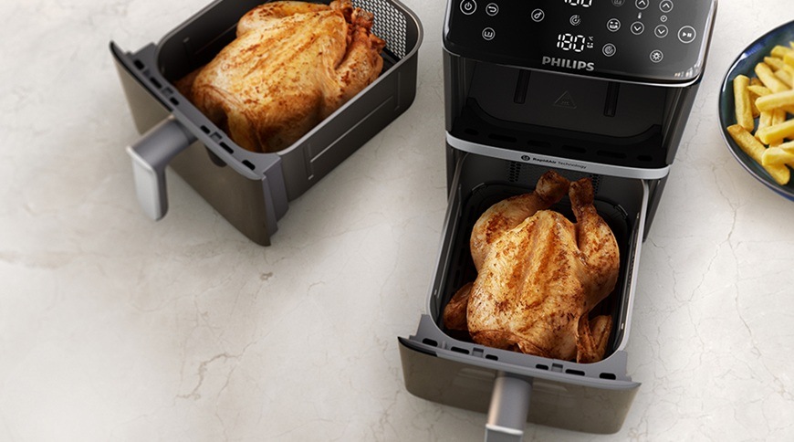 Fritéza horkovzdušná Philips Airfryer Dual Basket 4000 series 10 l, NA461/00 černá Horkovzdušná fritéza Philips NA461/00 se dvěma vysunutými koši, ve kterých jsou připravovaná celá kuřata, vedle na lince je talíř s hranolkami.