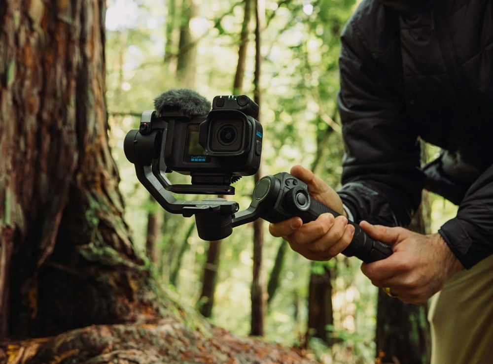 Outdoorová kamera GoPro MISSION 1 PRO Ultimate Creator Edition černá Tvůrce drží grip s kamerou při natáčení v lese