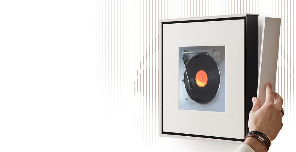 Reproduktory Samsung HW-LS60D, Music Frame (2 ks) černé Ruka přikládá rámeček na Samsung HW-LS60D, Music Frame pověšený na zdi