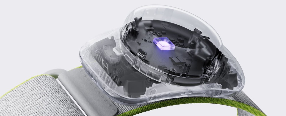 Snímač pohybu PICO Motion Tracker bílé Průřez snímačem s viditelnou deskou plošných spojů a svítícím fialovým světlem na šedozeleném látkovém popruhu. Moderní a technologicky zaměřený tón.