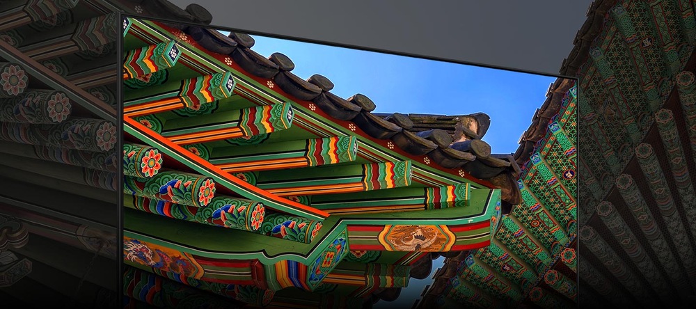 Malované střešní trámy, před nimiž je televize Samsung, obraz televize plynule přechází do okolí