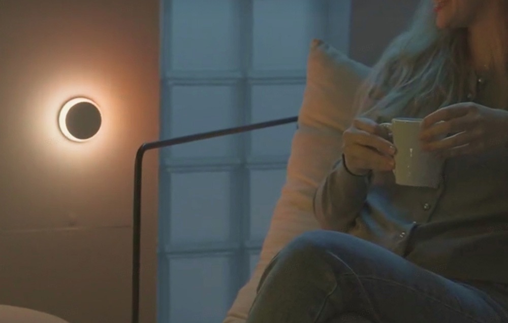 Noční světlo Yeelight Vega RGB NightLight se snímačem pohybu bílé Žena sedí v obývacím pokoji s šálkem čaje a v zásuvce má světlo Yeelight Vega RGB NightLight