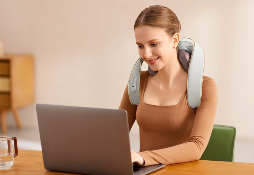 Žena používá masážní límec SKG H5 Mini při práci na notebooku