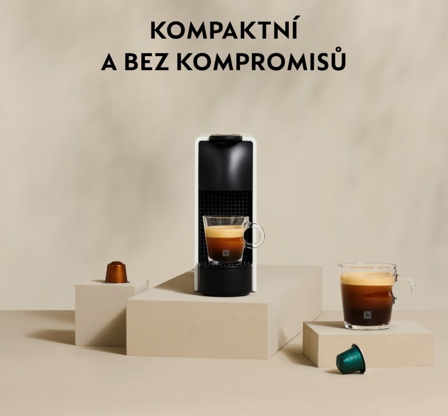 Kapslový kávovar Essenza Mini na kuchyňské desce se šálky kávy a kapslemi