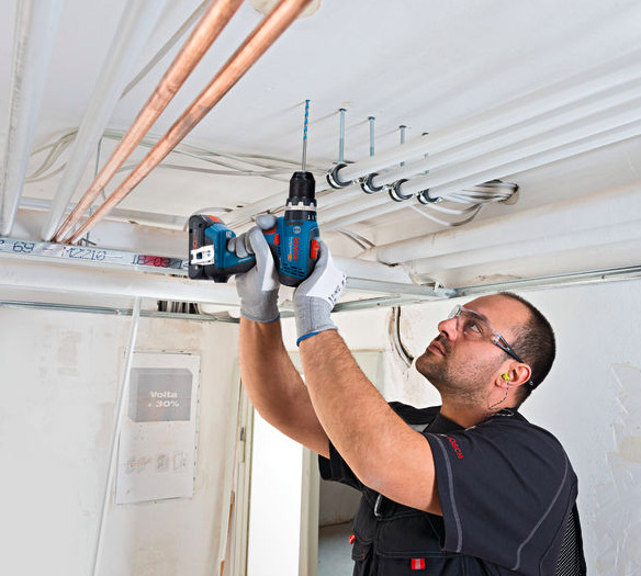 Vrtací šroubovák Bosch Professional GSB 18V-65 (s baterií) Řemeslník vrtající nad hlavou pomocí Bosch Professional GSB 18V-65 při montáži instalací