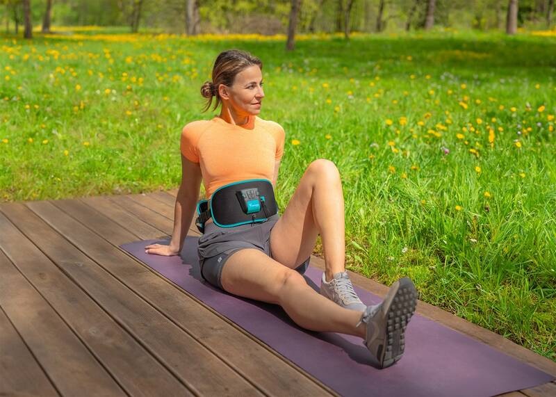 Elektrostimulátor Beurer Corefit II černý Žena cvičí na podložce v parku s nasazeným stimulátorem Beurer Corefit II