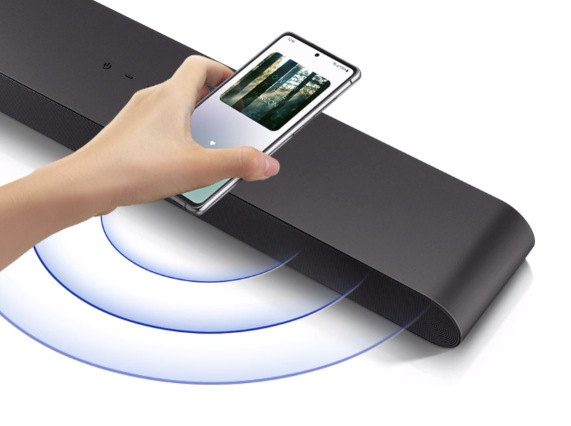 Soundbar Samsung HW-S50B černý Ruka drží mobilní telefon nad soundbarem Samsung HW-S50B, z nějž se šíří modré kroužky znázorňující zvuk