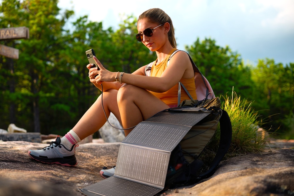 Žena s mobilem v ruce dobíjeným solárním panelem EcoFlow v přírodě