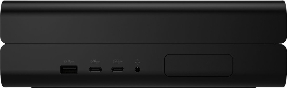PC mini HP Z2 Mini G1i černý Na obrázku je přední nebo boční panel kompaktního stolního počítače HP Z2 Mini G1i v černém provedení. Tělo má nízký, široký tvar s jemně zaoblenými hranami a hladkým matným povrchem. Vlevo jsou tři konektory na čelní straně – jeden klasický USB port a dva USB-C porty – vedle malý kulatý audio konektor pro sluchátka. Vpravo je větší obdélníkový kryt nebo záslepka.