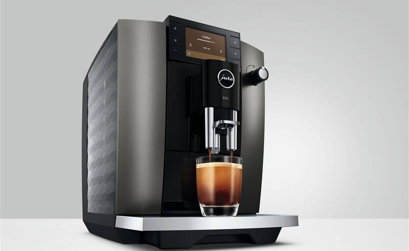 Automatický kávovar Jura E6 Dark Inox (ED) tmavě šedý Černý kávovar Jura E6 připravuje čerstvou kávu s bohatou krémou do sklenice na stole