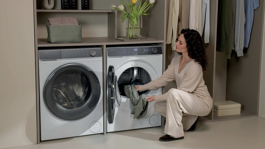 Sušička prádla Haier HD90-A367U1-S bílá žena vkládá prádlo do sušičky haier HD90-A367U1-S, která se nachází v prádelně vedle pračky