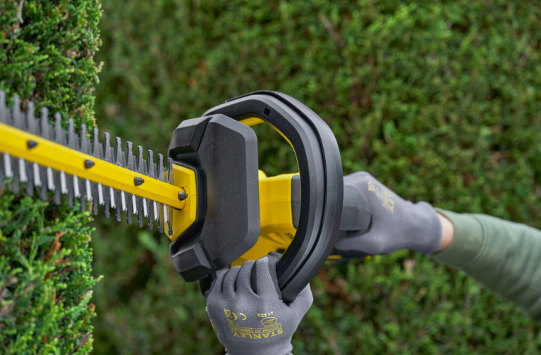 Nůžky na živý plot Stanley FatMax SFMCHT655M1-QW (s baterií) Detail ergonomické rukojeti nůžek Stanley FatMax SFMCHT655M1-QW při práci