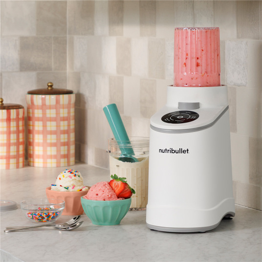 Nutribullet zmrzlinovač na kuchyňské lince s připravenou zmrzlinou a smoothie v miskách.