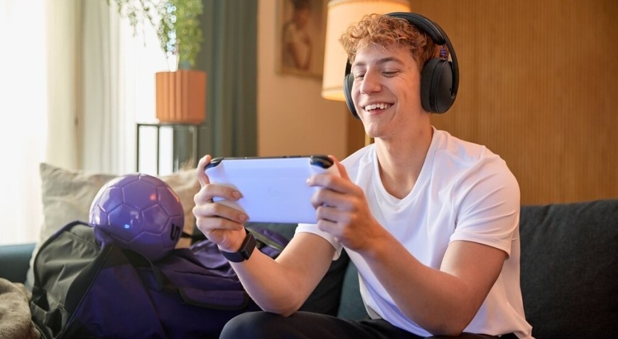 Hráč hraje mobilní hru na pohovce s nasazeným herním headsetem Logitech G325 LIGHTSPEED Wireless