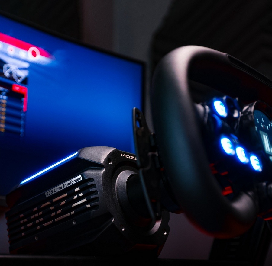 Základna Moza Racing R25 Ultra Direct Drive hliník Detailní záběr na závodní příslušenství s volantem se svítícími modře tlačítky a displejem zobrazujícím herní nastavení v tlumeně osvětlené místnosti.