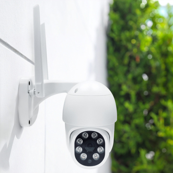 IP kamera Solight 1D76S bílá Venkovní bezpečnostní kamera připevněná na zdi u zahrady.