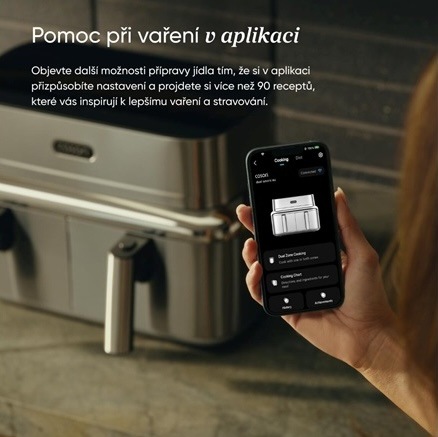 Žena drží v ruce smartphone s ovládací aplikací pro horkovzdušnou fritézu COSORI Iconic v moderní kuchyni