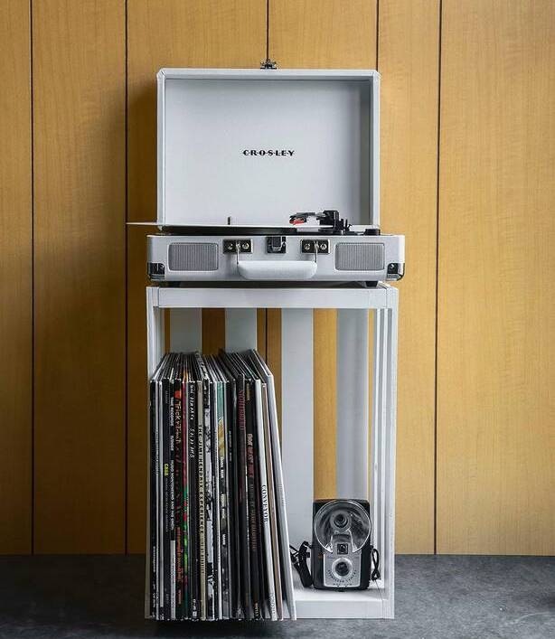 Gramofon Crosley Cruiser Plus bílý kufříkový gramofon Crosley Cruiser Plus bílý umístěný na stojanu v interiéru s deskami pod gramofonem
