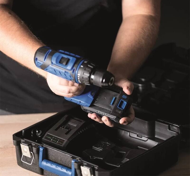 Vrtací šroubovák Scheppach C-DTB74/1-X - 20 V IXES (s baterií) Muž v dílně nasazuje 20V lithium-iontovou baterii na aku vrtačku Scheppach nad otevřeným kufrem