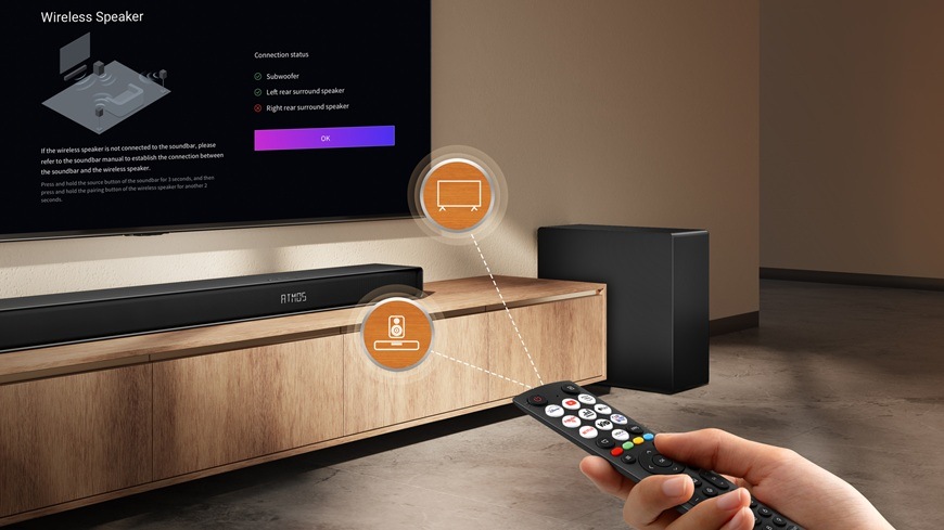 Soundbar Hisense AX5140Q a bezdrátový subwoofer v moderním obývacím pokoji. Žena ovládá domácí kino pomocí dálkového ovladače.