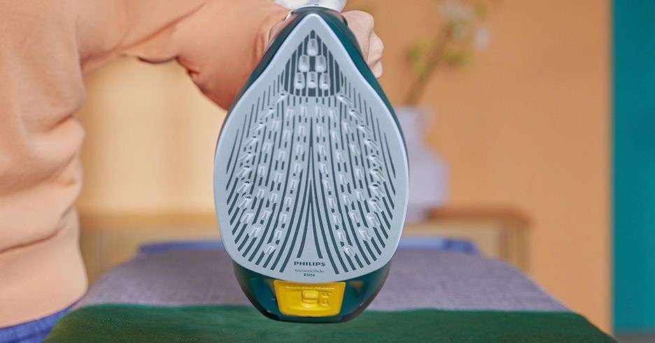 Žehlička Philips Series 7000 DST7050/70 zelená Díváme se na spodní část žehličky, její žehlicí keramickou plochu s rovnoměrně rozmístěnými otvory na průchod páry.
