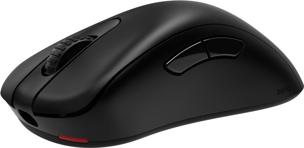 Na obrázku je bezdrátová herní myš ZOWIE by BenQ EC1-DW z bočního pohledu. Má matně černé provedení, výrazně prohnutý ergonomický tvar pro pravou ruku a dvě boční tlačítka pro palec. Vpředu je vidět otvor pro nabíjecí kabel, nahoře rolovací kolečko a na spodní přední části malý červený detail. Myš působí jednoduše, bez podsvícení a s důrazem na pohodlný úchop.