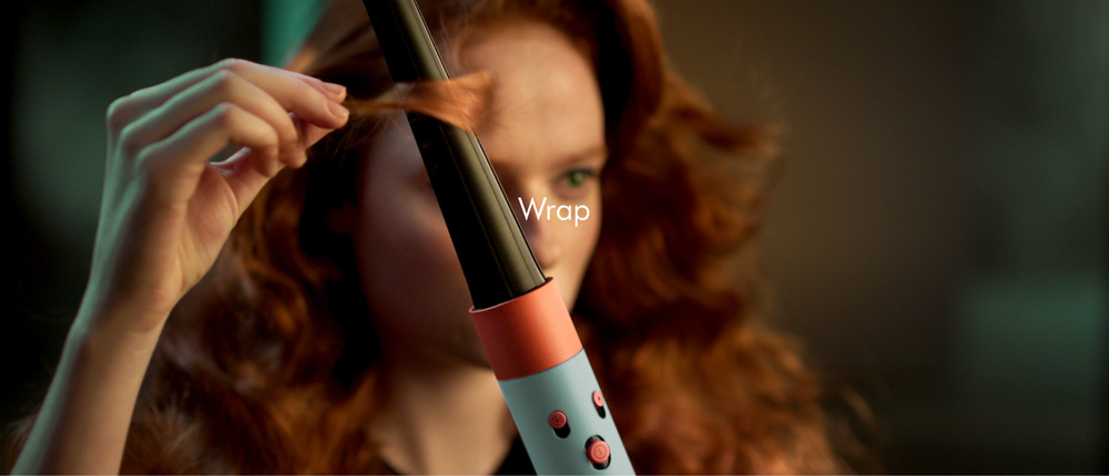 Multistyler Dyson Airwrap i.d. HS08 T3/T4 rose gold/ceramic pink Lifestyle stylingový moment, osoba natáčí pramen vlasů s kulmovým nástavcem, práce s horkým vzduchem, dynamický pohyb pramene, precizní úchop během tvorby lokny