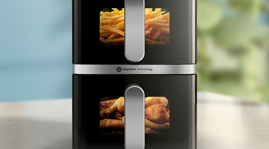 Fritéza horkovzdušná Philips Airfryer Dual Basket 4000 series 10 l, NA461/00 černá Detail horkovzdušné fritézy Philips NA461/00 se dvěma koši, ve kterých jsou přes průhledná okénka vidět hranolky v horní části a kuřecí paličky ve spodní části, uprostřed je označení technologie RapidAir.