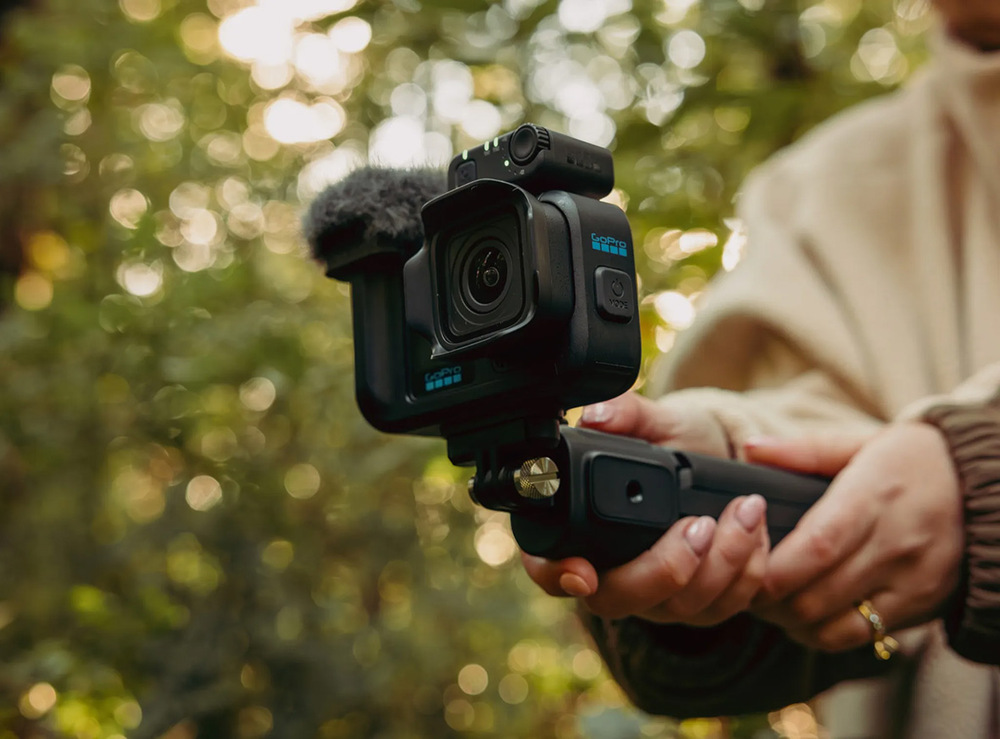 Outdoorová kamera GoPro MISSION 1 PRO Creator Edition černá Ruce držící kameru GoPro s mikrofonem během natáčení v přírodě