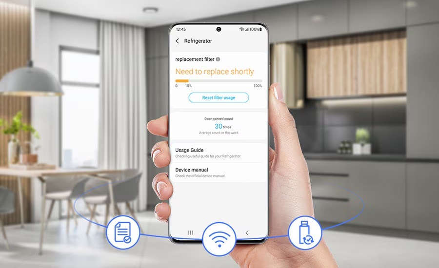 Americká lednice Samsung RF24BB620EB1EO černá Ruka drží mobilní telefon s aplikací SmartThings Home Care, na pozadí je kuchyně