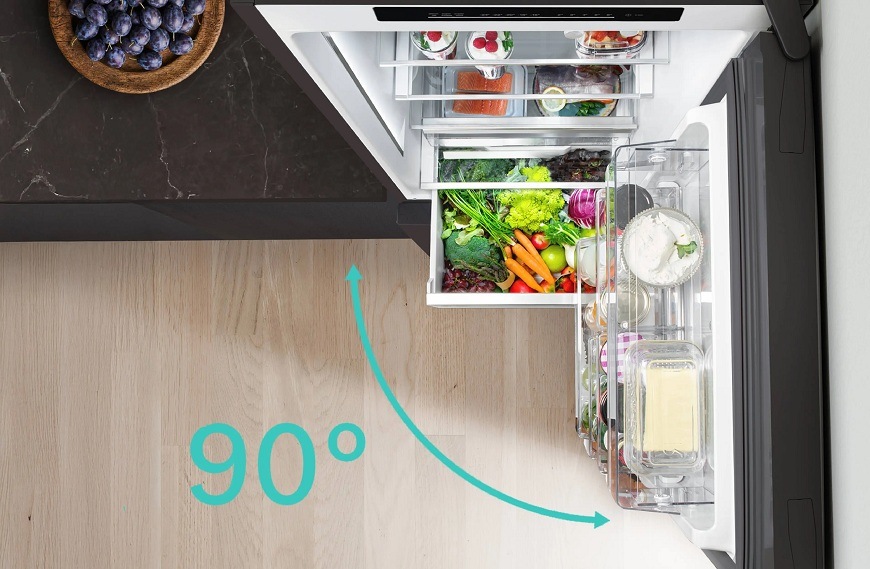 Otevřená lednice Siemens v tmavé kuchyni přisunutá přímo ke zdi a nábytku díky systému noDistance, znázorněná možnost otevírání na 90 °