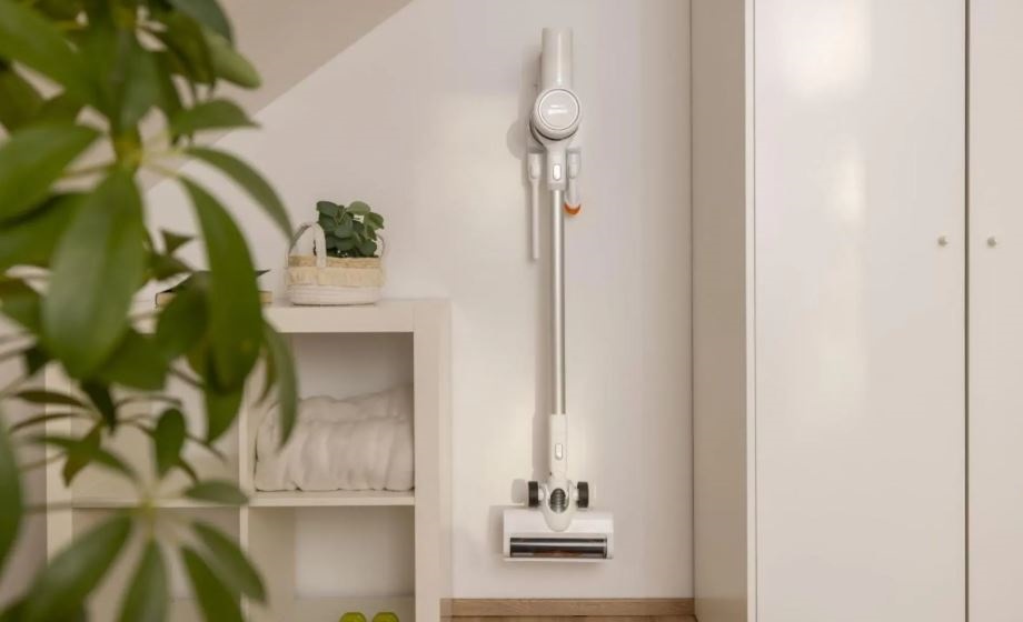 Tyčový vysavač Gorenje SVC216290FFW FreeForce bílý tyčový vysavač Gorenje SVC216290FFW vidí na zdi ve svém držáku. Kolem jsou rostliny a vše je osvětleno sluncem.