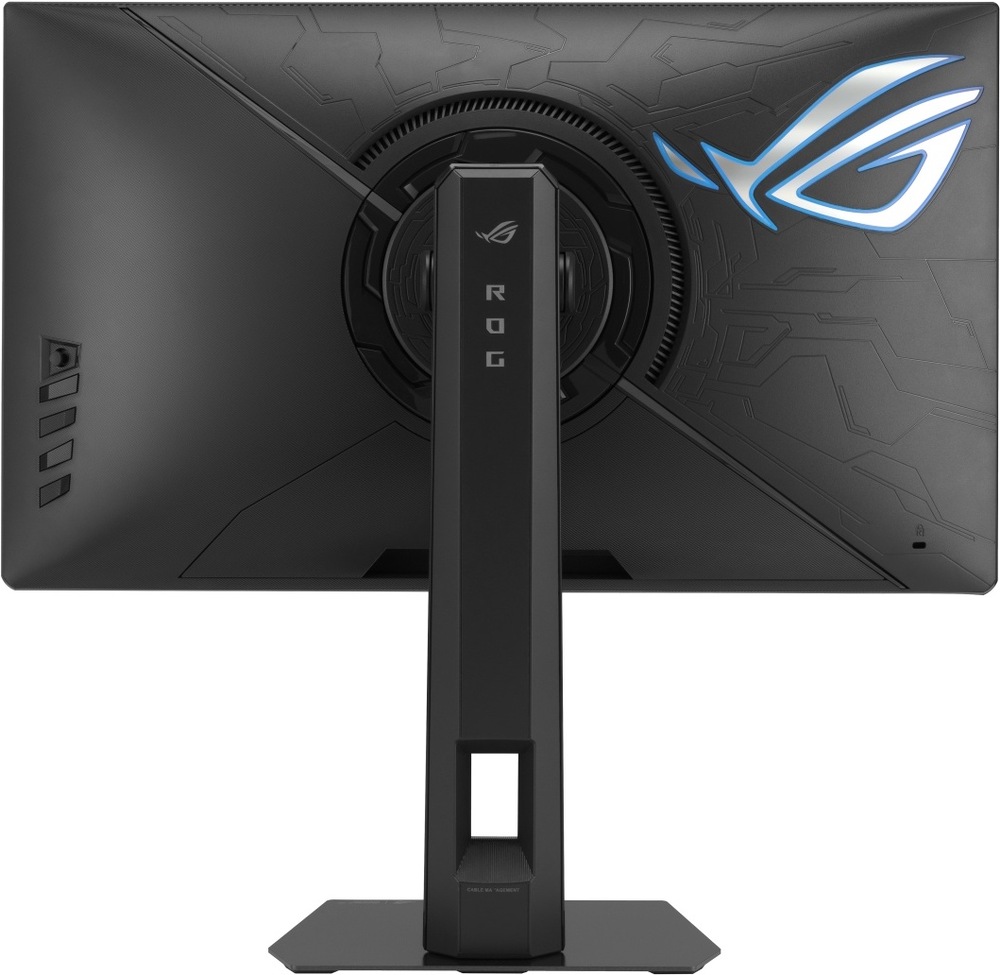 Herní monitor Asus ROG Strix XG248QSG Ace černý Na obrázku je zadní strana herního monitoru ASUS ROG Strix. Monitor má černé tělo s výrazným herním vzorem a velkým podsvíceným logem ROG v pravé části. Uprostřed je kruhový kloub pro natočení monitoru a pevný výškově nastavitelný stojan s nápisem ROG. Ve spodní části stojanu je otvor pro vedení kabelů a dole plochá hranatá základna. Vlevo na zadní straně jsou vidět ovládací tlačítka monitoru.