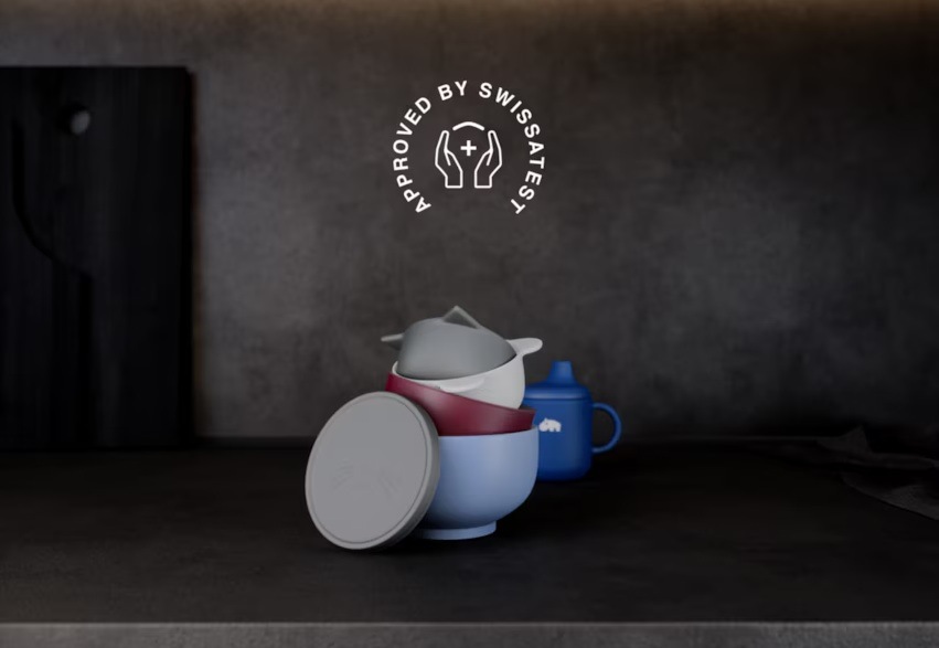 Dětské nádobí na kuchyňské lince. Nad ním symbol Approved by SwissAtest.