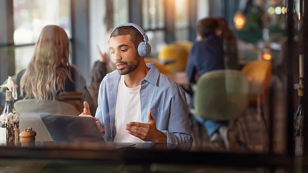 Sluchátka Philips TAH4500WT/00 bílá Muž v kavárně telefonuje pomocí notebooku a sluchátek Philips TAH4500