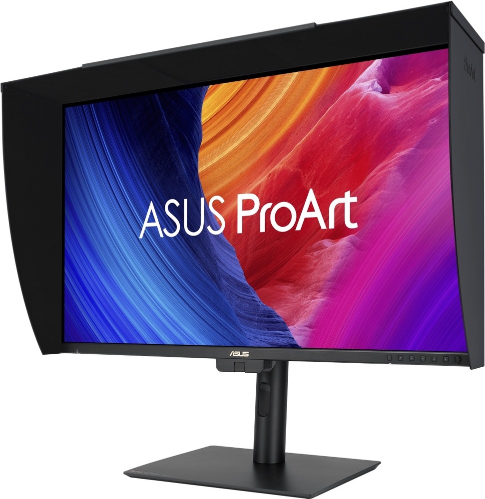 Na obrázku je monitor Asus ProArt PA27UCGE 27" z předního šikmého pohledu. Displej je osazený černou stínicí clonou po horní a bočních stranách, která omezuje rušivé okolní světlo. Monitor stojí na černém výškově nastavitelném stojanu s plochou základnou a otvorem pro vedení kabelů. Na obrazovce je barevná grafika ASUS ProArt v modrých, oranžových, červených a fialových tónech. Vpravo dole na spodním rámečku jsou vidět ovládací tlačítka.