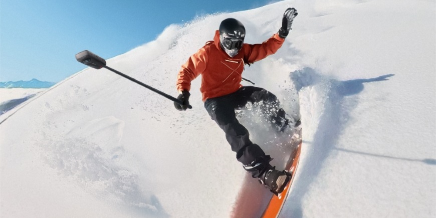 Muž jedoucí na snowboardu má kameru Insta360 X5 upevněnou na selfie tyči