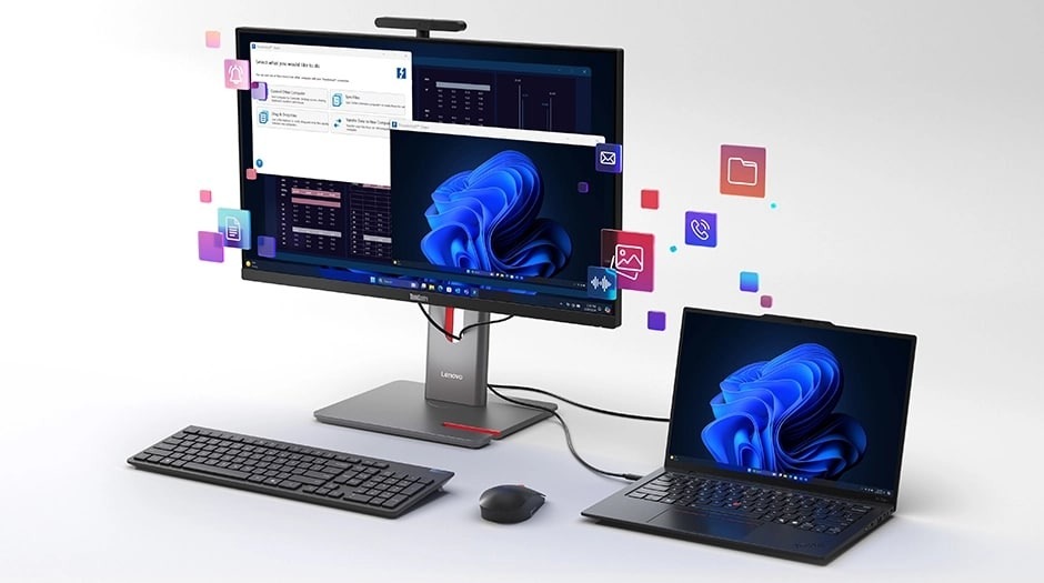 All In One počítač je připojený k notebooku s klávesnicí a myší před nimi. Po obrazovce se vznášejí ikony různých aplikací, které naznačují multitasking nebo používání více aplikací.