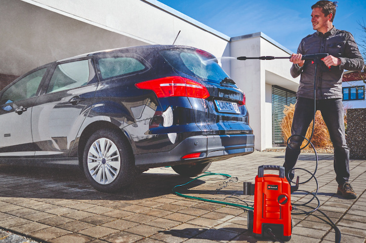 Muž používá vysokotlaký čistič Einhell Expert TC-HP 130 při mytí automobilu na příjezdové cestě
