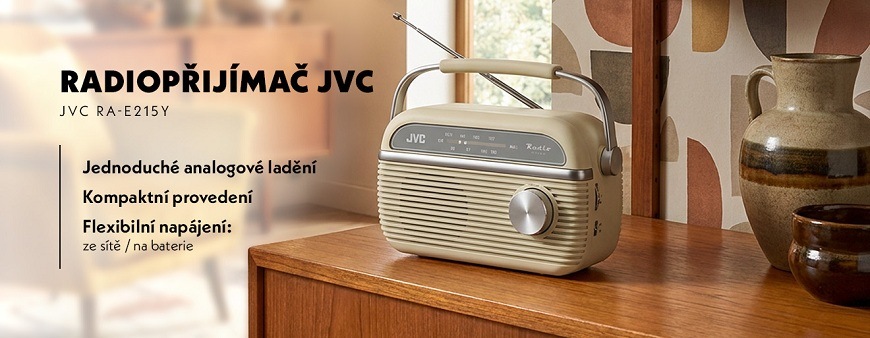 Radiopřijímač JVC RA-E215Y béžový Retro radiopřijímač JVC RA-E215Y v béžové barvě na dřevěné komodě. Text v obrázku vyzdvihuje jednoduché analogové ladění, kompaktní provedení a flexibilní napájení ze sítě nebo na baterie