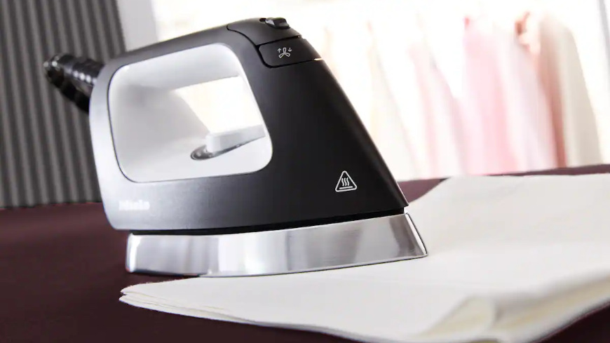 Žehlicí systém Miele B4847 FashionMaster 4.0 Žehlička položená na přeložené bílé utěrce