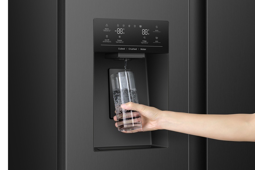 Detailní záběr na dávkovač ledu a chlazené vody. Paní si plní sklenici chlazenou vodou.