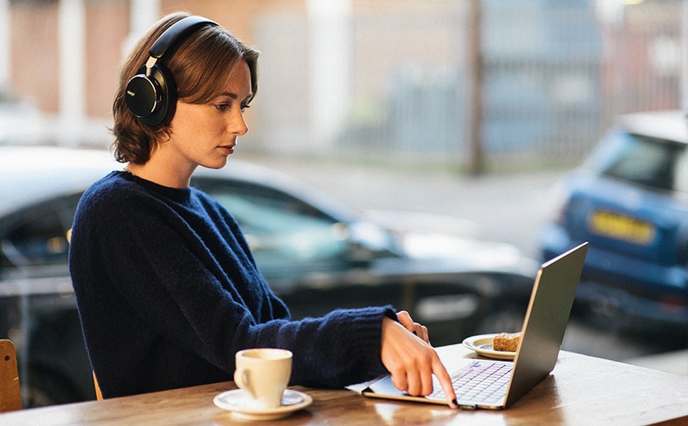 Sluchátka AKG N9 Hybrid bílá Žena pracující na notebooku v kavárně má na hlavě sluchátka Anker soundcore AKG N9 Hybrid