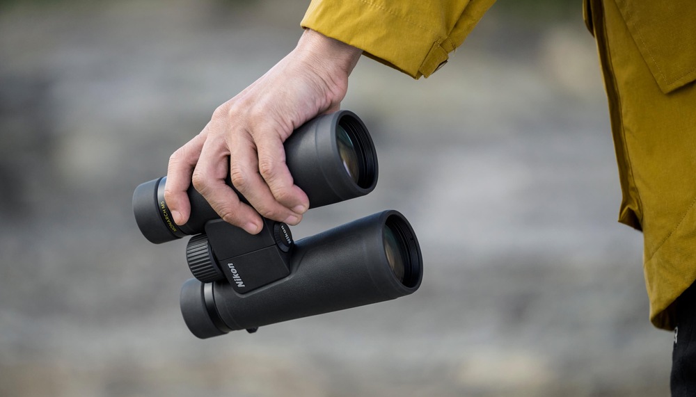 Dalekohled Nikon Monarch M5 12×50 černý Lehký a kompaktní dalekohled Nikon Monarch M5 12×50 držený v ruce při pobytu v přírodě