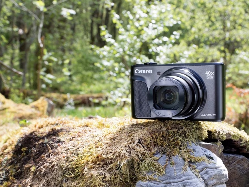 Digitální fotoaparát Canon PowerShot SX740 HS, TRAVEL KIT II stříbrný Přenosný kompaktní foťák PowerShot SX740 HS LITE EDITION položený v lese