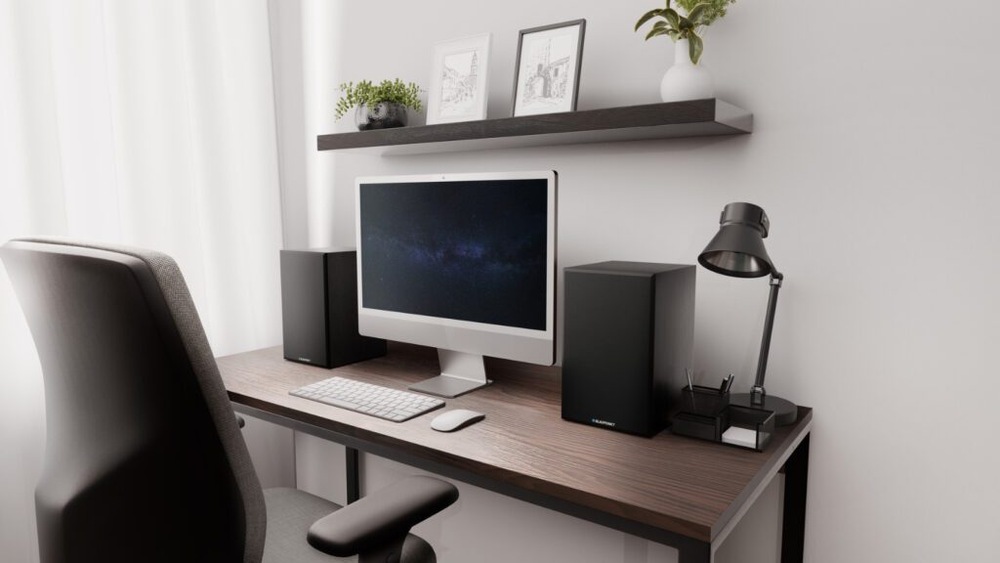 Reproduktory Blaupunkt umístěné na stole vedle monitoru.